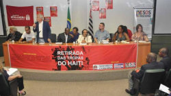 Julio fala durante ato, ao lado de Moise, Diogo e representantes dos movimentos sociais
