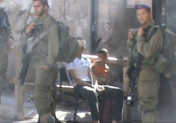 Imagem feita pela B'Tselem mostra o garoto Wadi ao lado do pai, vendado, em posto militar israelense